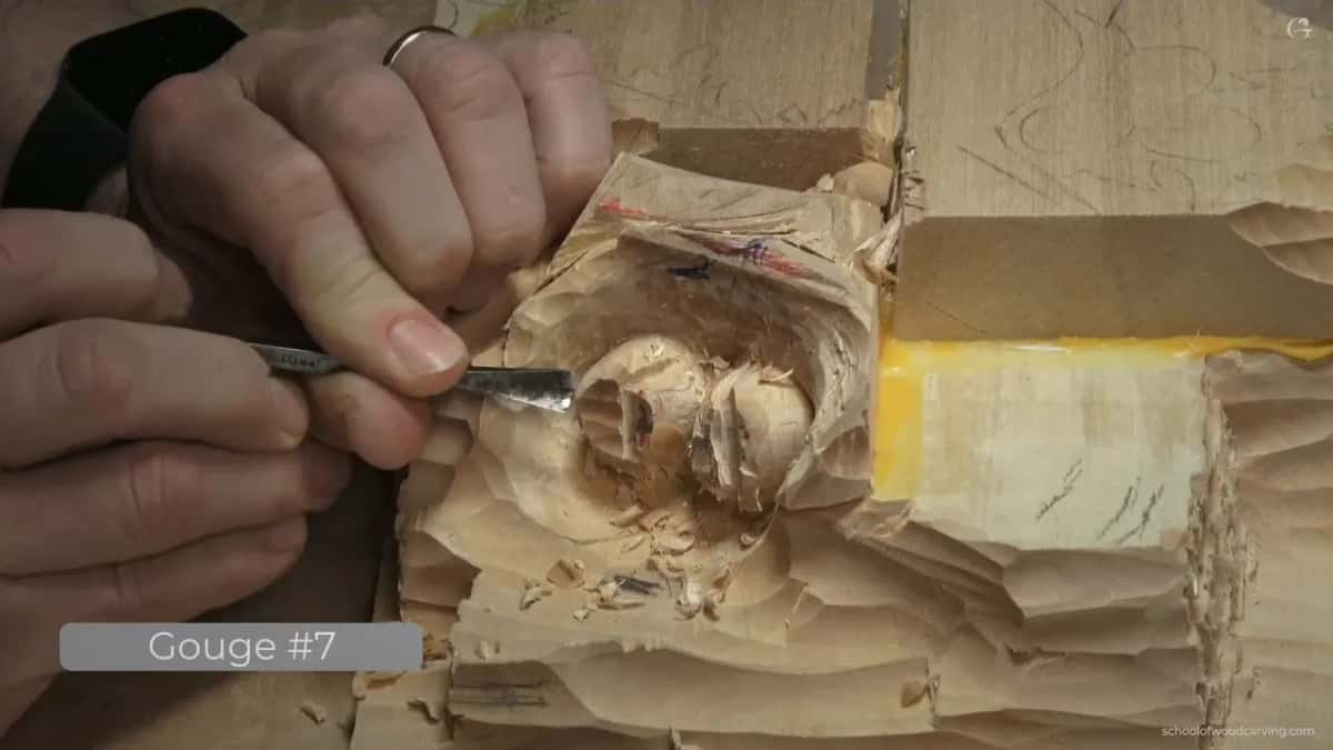 On-screen label reads Gouge #7 while two fingers steer the edge along the top of one carved hazelnut