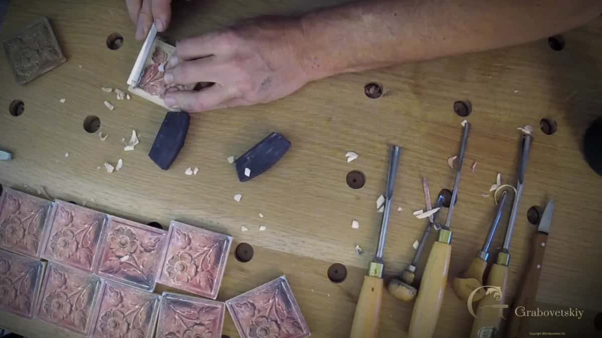 Glued blanks in two rows, gouges laid out beside them, the first rosette in hand