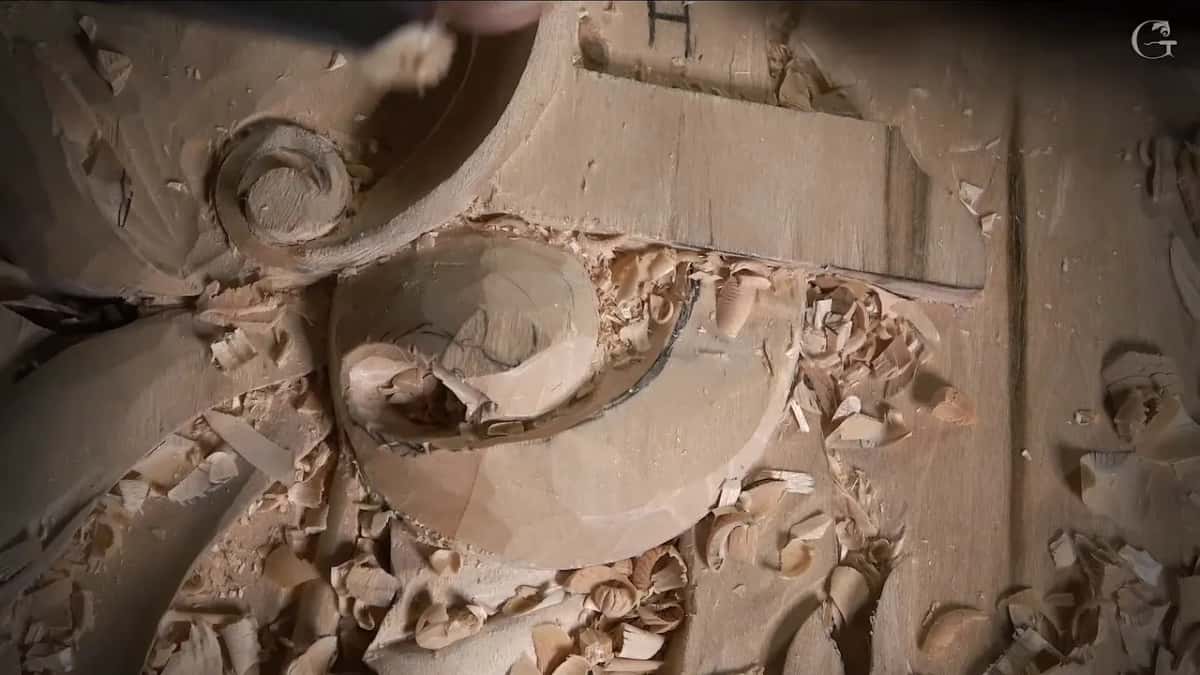A small tool reaches under the curl while chips pile up around it