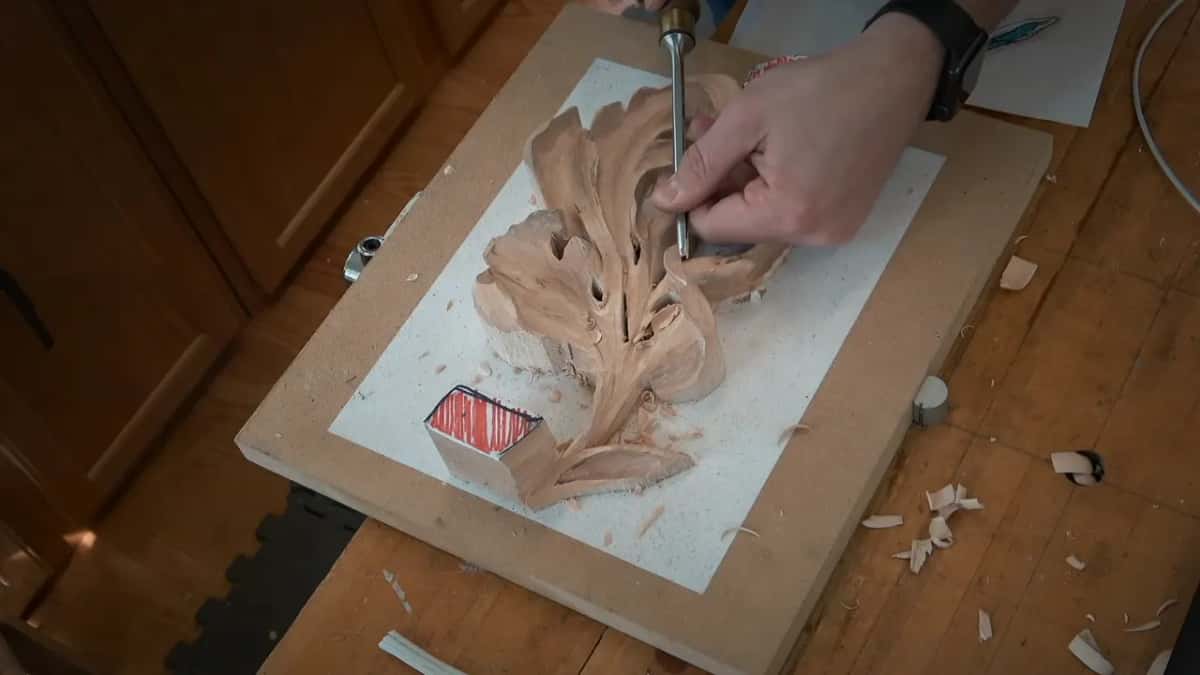 A gouge stands nearly upright in the middle of the leaf, fingers holding it close to the blade