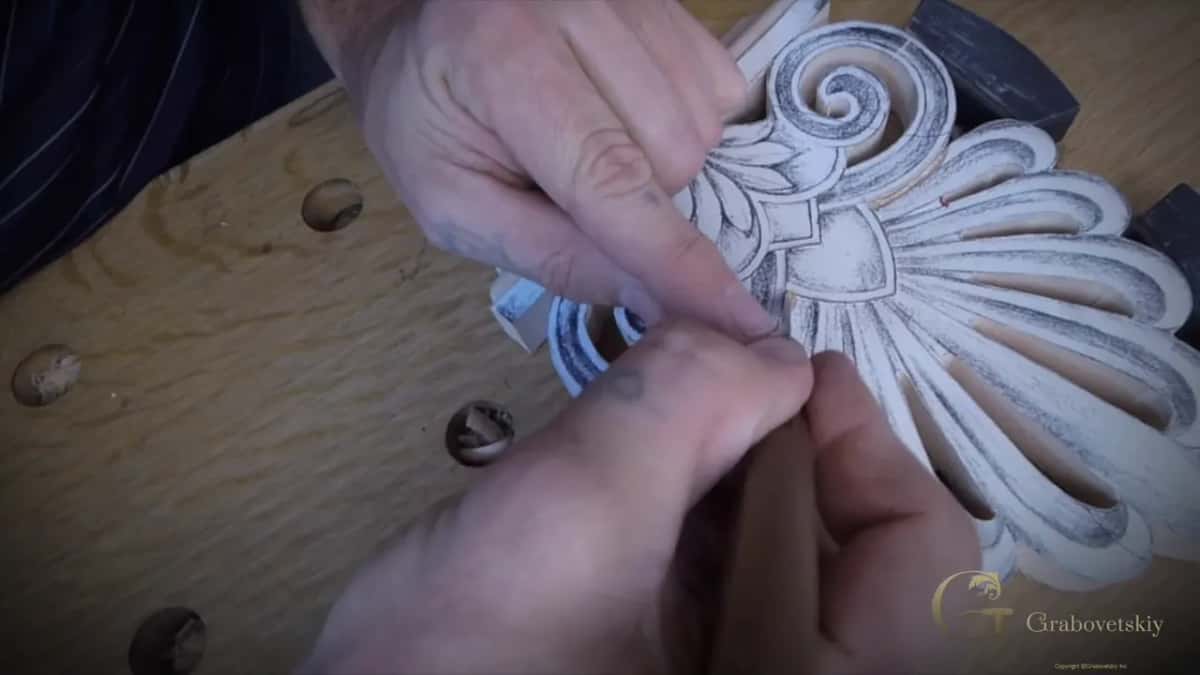 Two hands steer the knife down into the waste beside the base while a curl lifts off