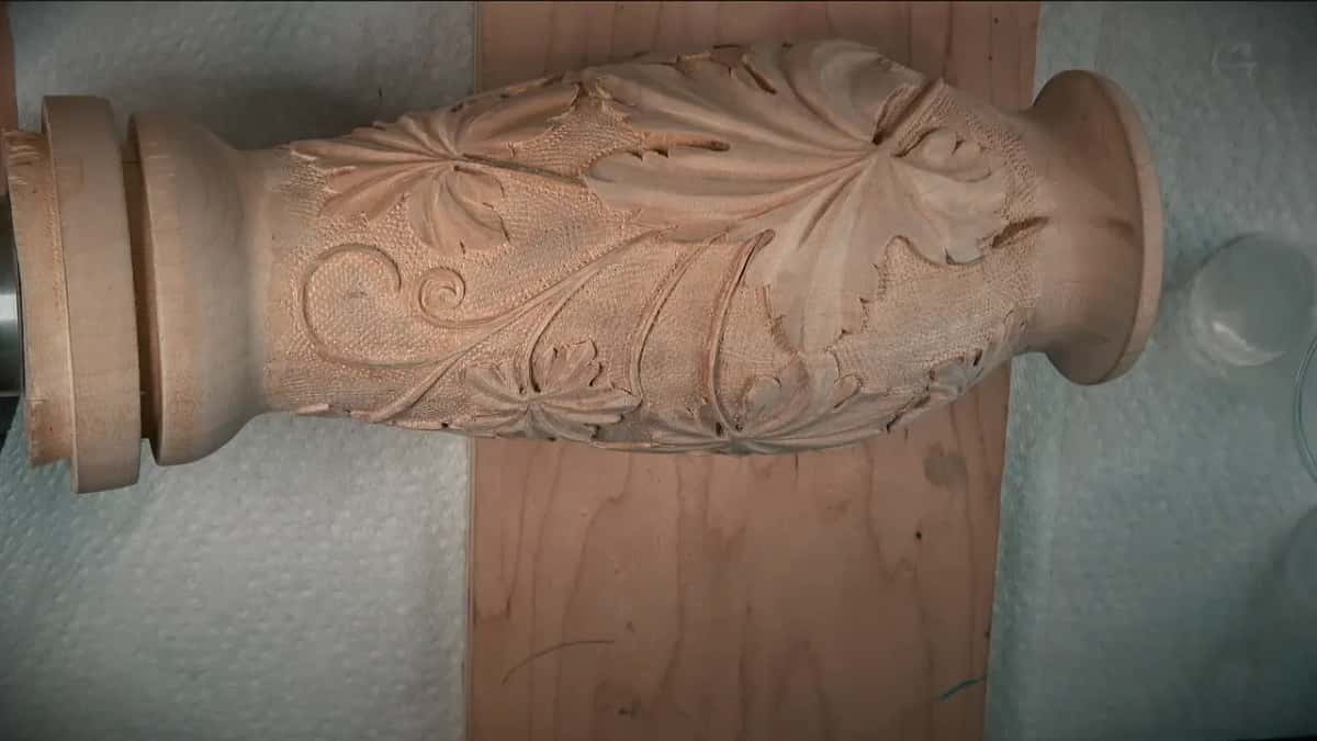 Lying on paper towels, the carved grape leaf vase shows its punched background and curling stems.
