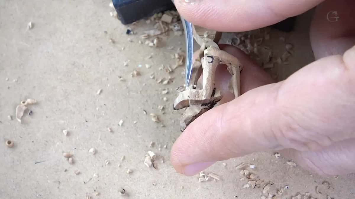 Fingertips holding a tiny carved lily over sawdust