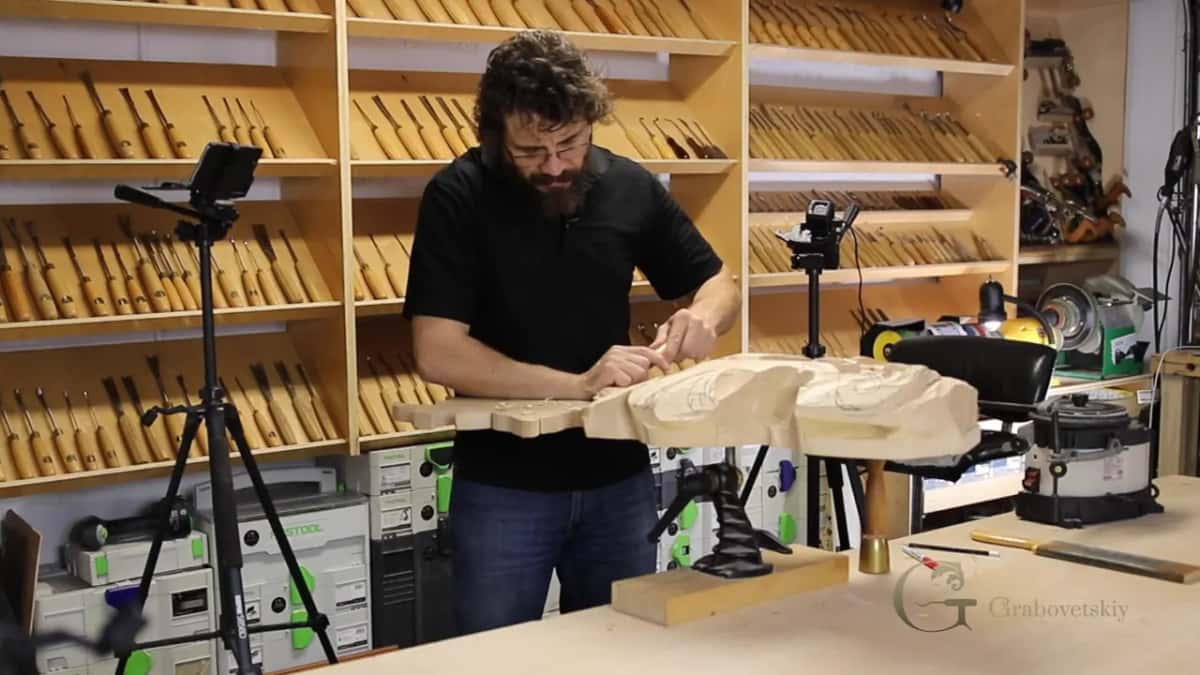 Leaning in over the scalloped end, tool in both hands