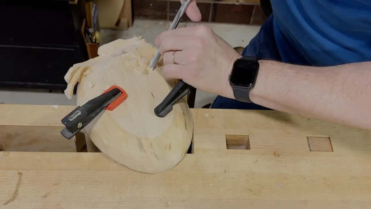 A slim tool is held like a pen, its edge down among the grapes of the clamped tray