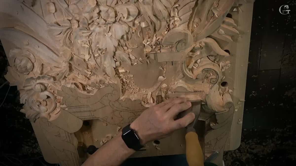 Hand pressing a wide chisel against a drawn line near the molding