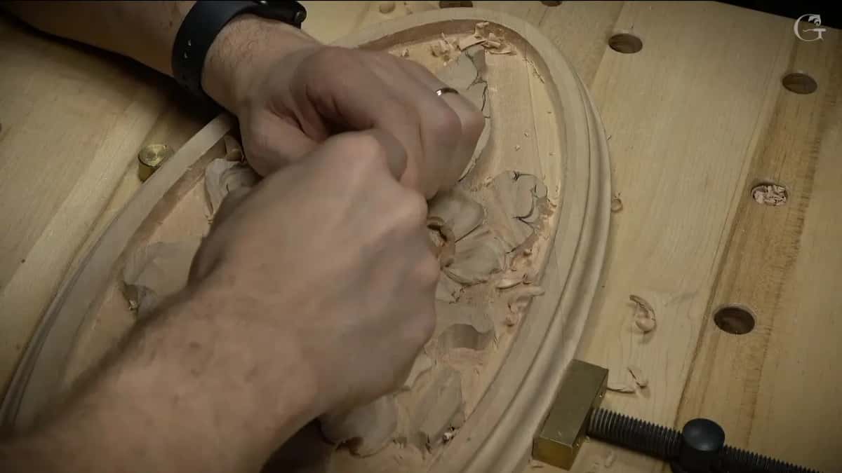 Two hands on one gouge, pressing it along the leaf by the rim
