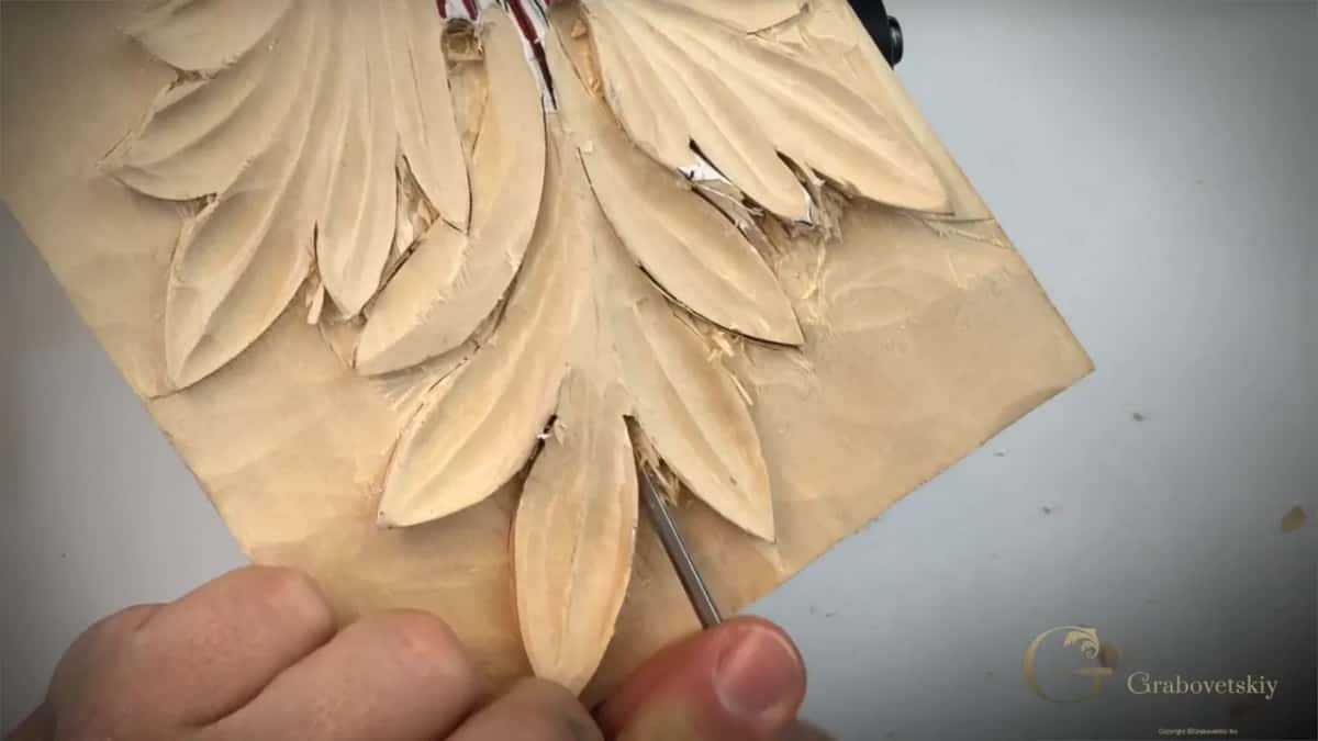 Narrow straight tool down in the gap beside the lowest acanthus lobe, shavings on the paper
