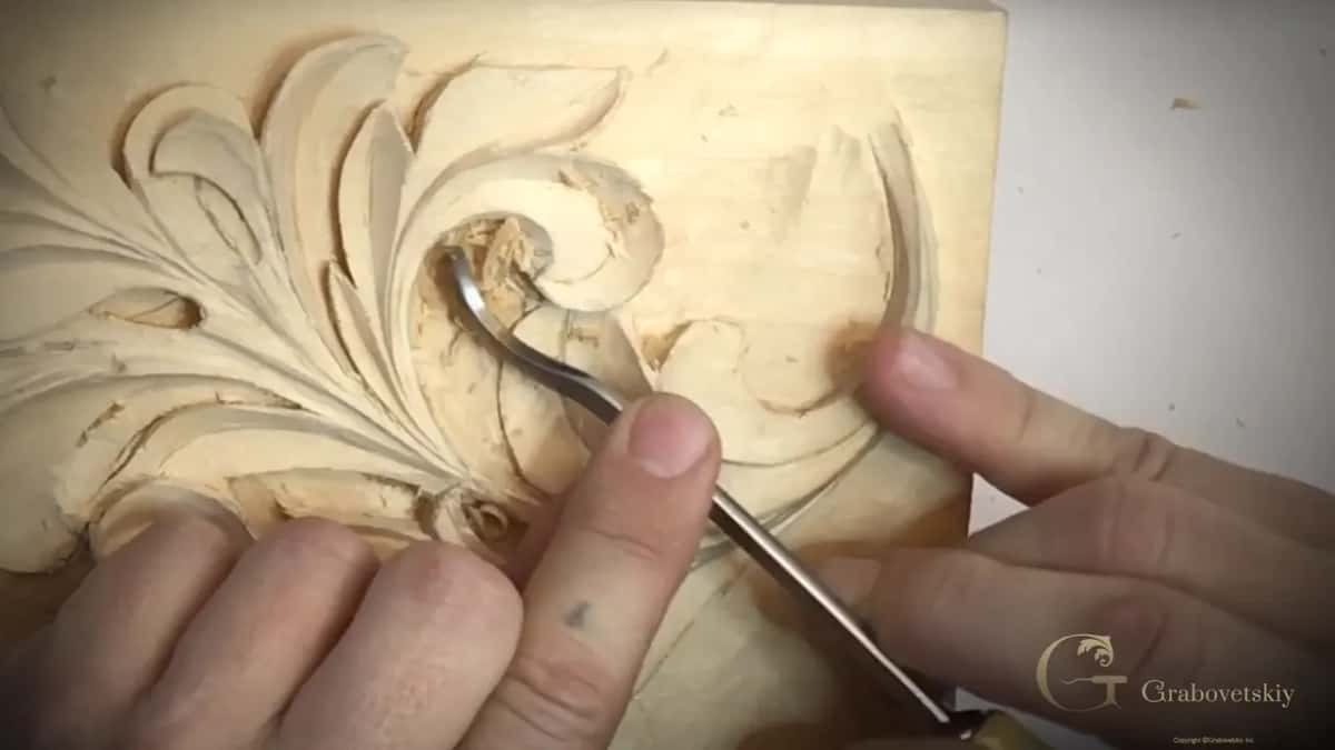 Bent shank reaching into the hollow of an acanthus scroll on a pale board