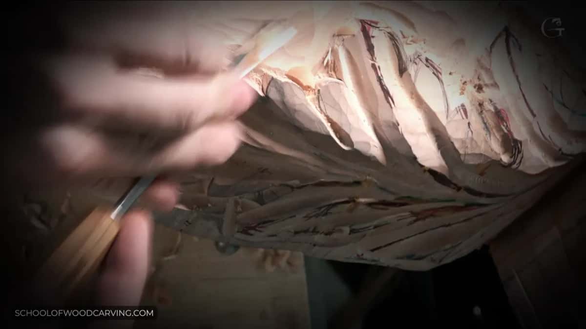 One hand guides a gouge into a Venetian acanthus leaf on the corbel