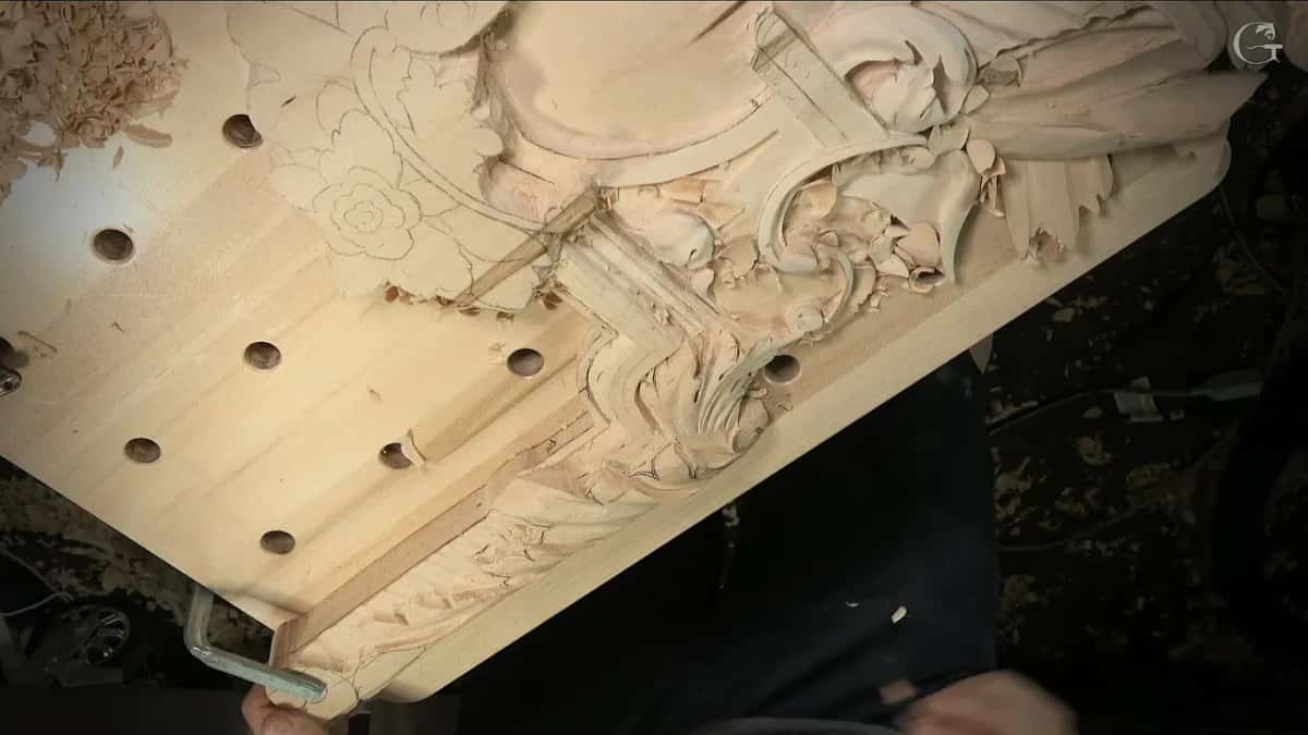 Overview of the Venetian panel from above, a pencil rosette still waiting beside the carved scrolls and molding