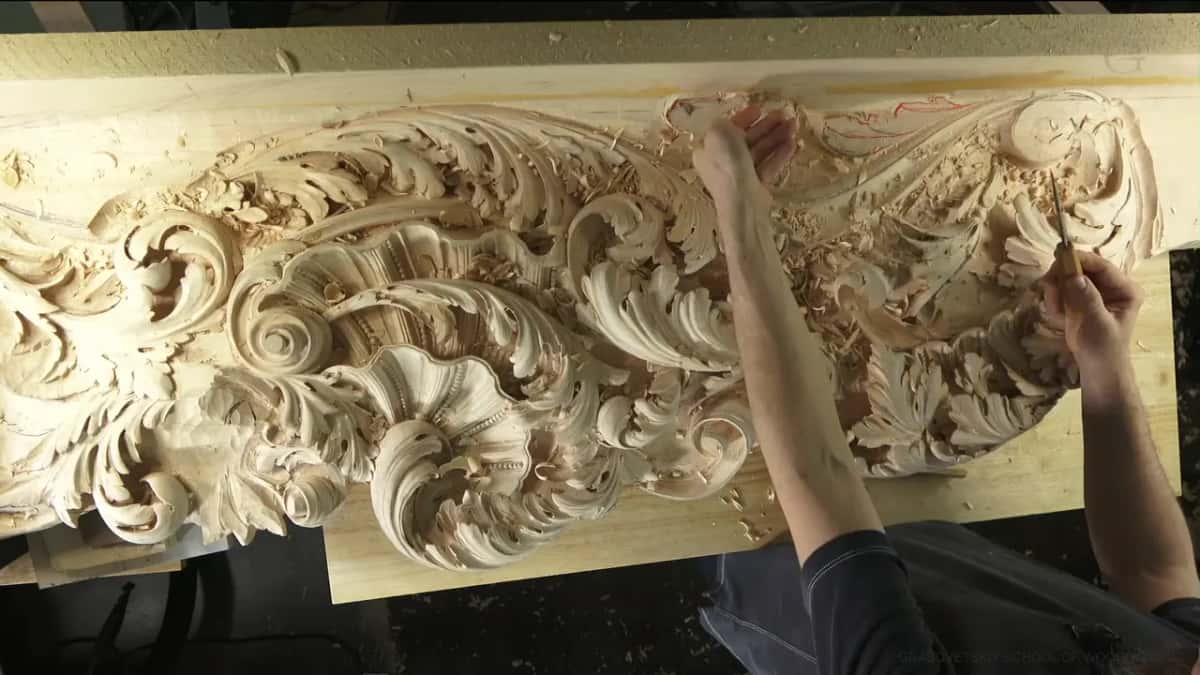Seen straight down, one hand near a top scroll and a tool in the other