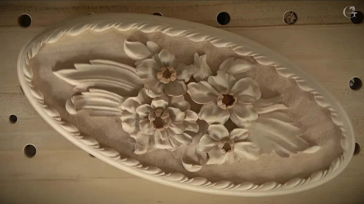 The finished oval, its carved border circling the flowers on a textured ground