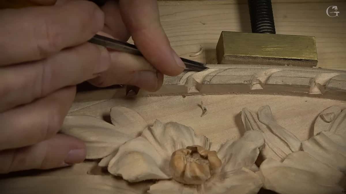 Fingertips guide a narrow gouge into one border unit