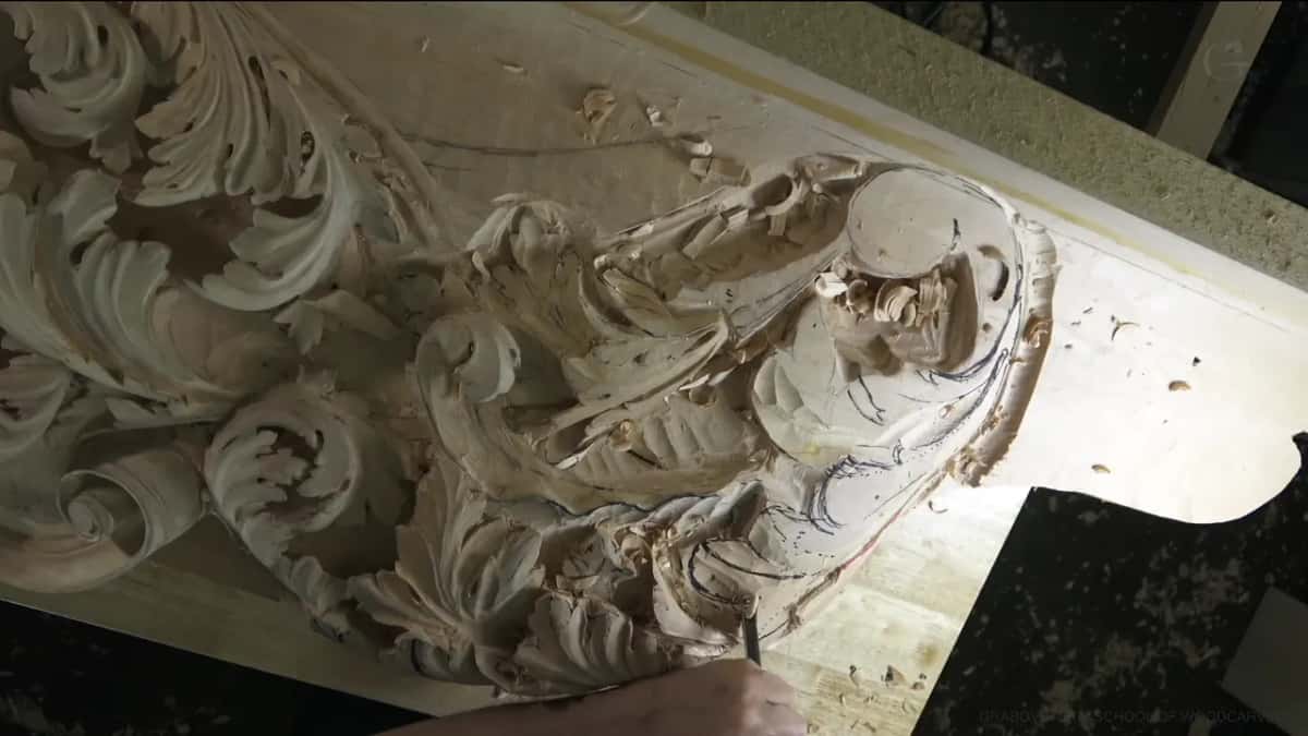 Seen from overhead, deep acanthus leaves curl around a flat round disc on a big board, one hand at its edge