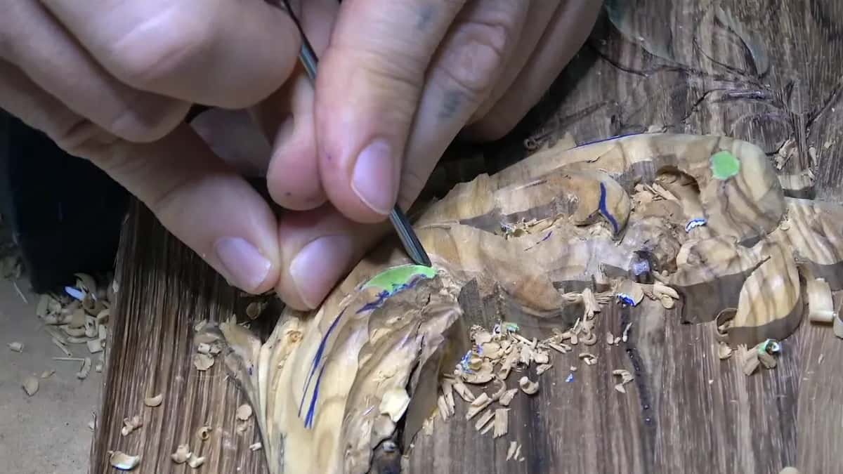 Fingertips steer a needle-thin tool into a petal.
