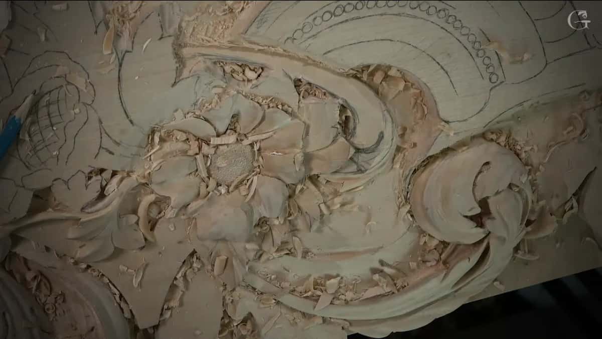 Loose chips lie across a half-carved panel of scrolls and flowers.