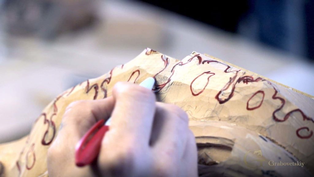 A person is carefully tracing a design on a piece of wood while preparing for wood carving lessons. This scene highlights the focus and creativity involved in wood carving classes, where learners explore tools and techniques to bring their ideas to life.