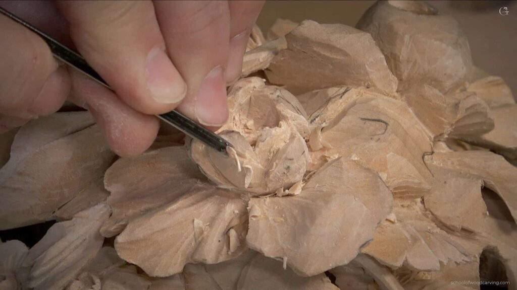 WOODCARVING LESSONS: Close-up of Woodcarver Grabovetskiy's hand using a carving tool to shape flower designs on wood. - Wood Carving tutorials