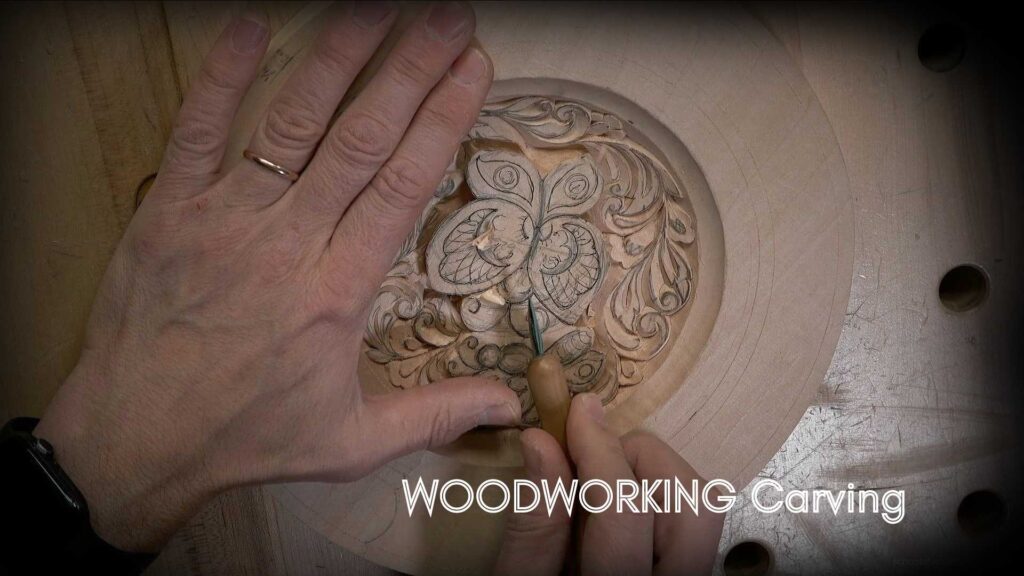 WOODCARVING LESSONS: A person, Woodcarver Grabovetskiy, uses a hand tool to carve a butterfly design into wood. The image says "WOODWORKING Carving." beginner tips for woodworking carving and learn the art of wood carving. - Wood Carving tutorials